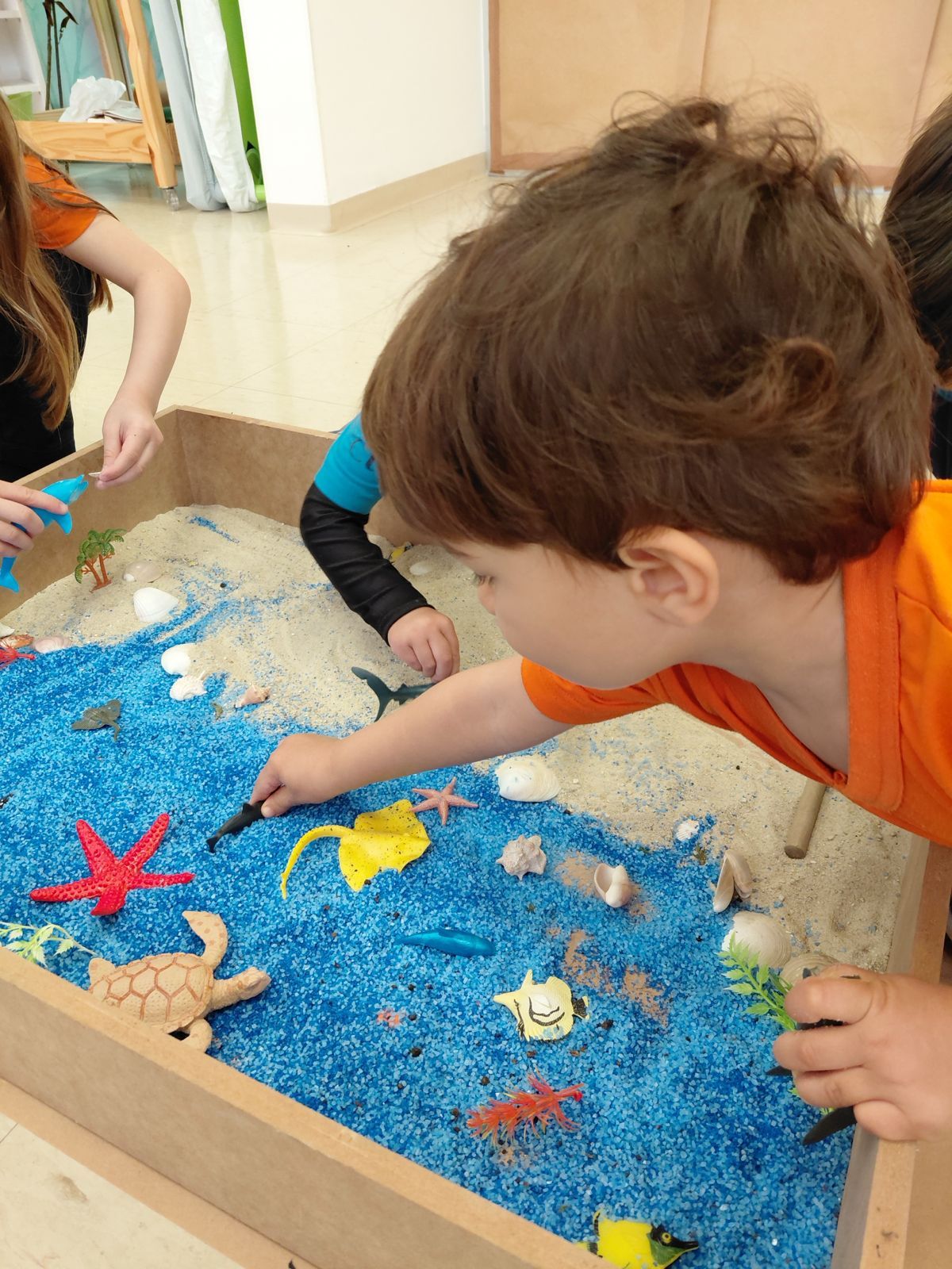 Criança explorando uma caixa sensorial com animais do mar